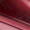 The sleek, glossy red surface of the Jazzy Elite ES showcases smooth curves with an interplay of light and shadows, resembling a cars exterior and highlighting its shiny finish.