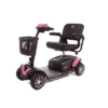 The Golden 4 wheel Buzzaround EX is a pink and black mobility scooter featuring four wheels, a comfortable padded seat, armrests, and a front storage basket.