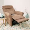 A Pride VivaLift!® Urbana 2 Model PLR-965 recliner is partially extended in a bright room. A small wooden side table holds a blue mug, book, and pen. Decorative white flowers in a vase and a patterned rug enhance the welcoming atmosphere.