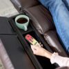 Relaxing in the Golden Technologies®️ Cloud+ Power Lift Recliner PR 511, a person in blue jeans and a pink sweater holds a remote. Their feet are up, with coffee in a compartment beside them.